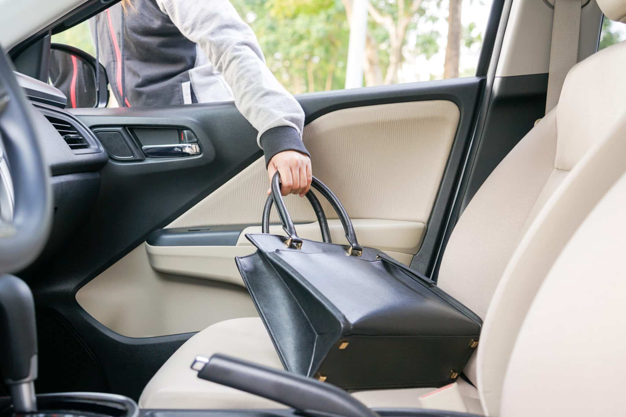 A person in a hoodie reaches into a car to pick up a handbag | Weygandt Law LLC